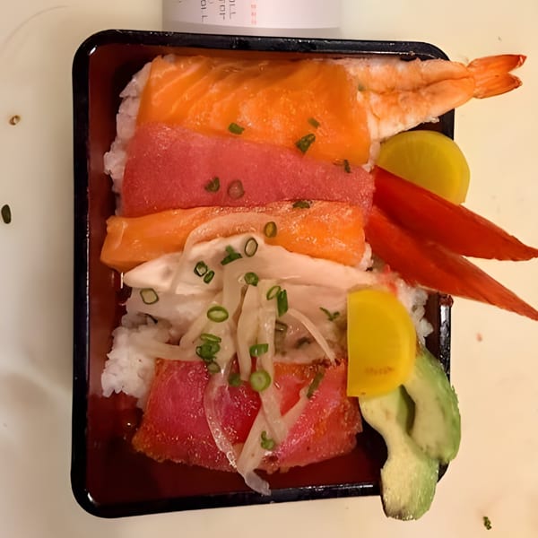 Ahi Sushi & Grill's chirashi bowl with salmon, tuna, shrimp, and various toppings in a black container.