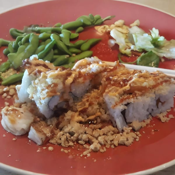 Ahi Sushi & Grill's sushi rolls with sauce and crispy toppings, served with edamame and salad.